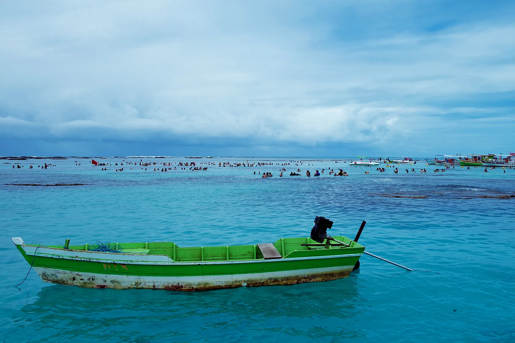 Vista aérea do mar de Antunes, com águas azuis e corais com turistas em barcos.