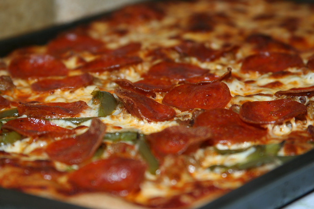 Pizzarias em Maceió: Pizza de queijo com fatias de calabresa por cima pronta para consumo.
