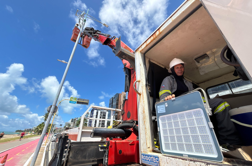 Homem controlando equipamento de instalação de poste na orla.